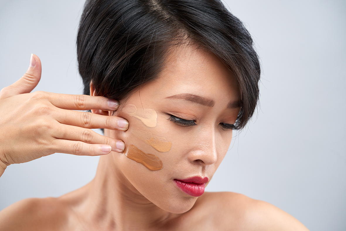 Une femme essaie sur son visage différentes teintes de fond de teint minéral crémeux.