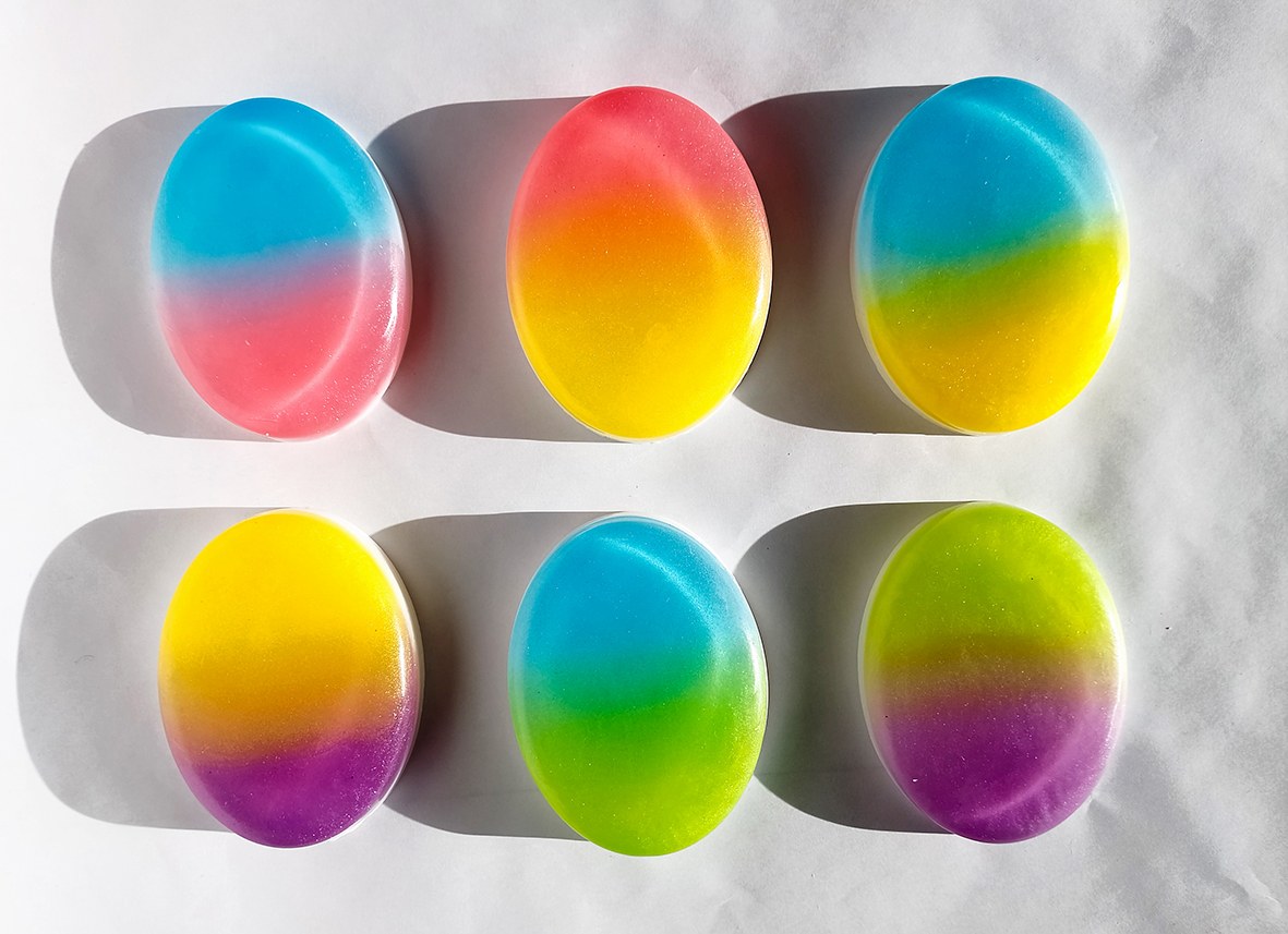 Six bars of ombré soap neatly lined up on a white background.