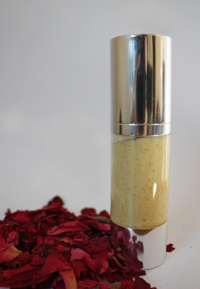 Homemade day cream filled into a silver airless bottle, with dried rose petals beside it.
