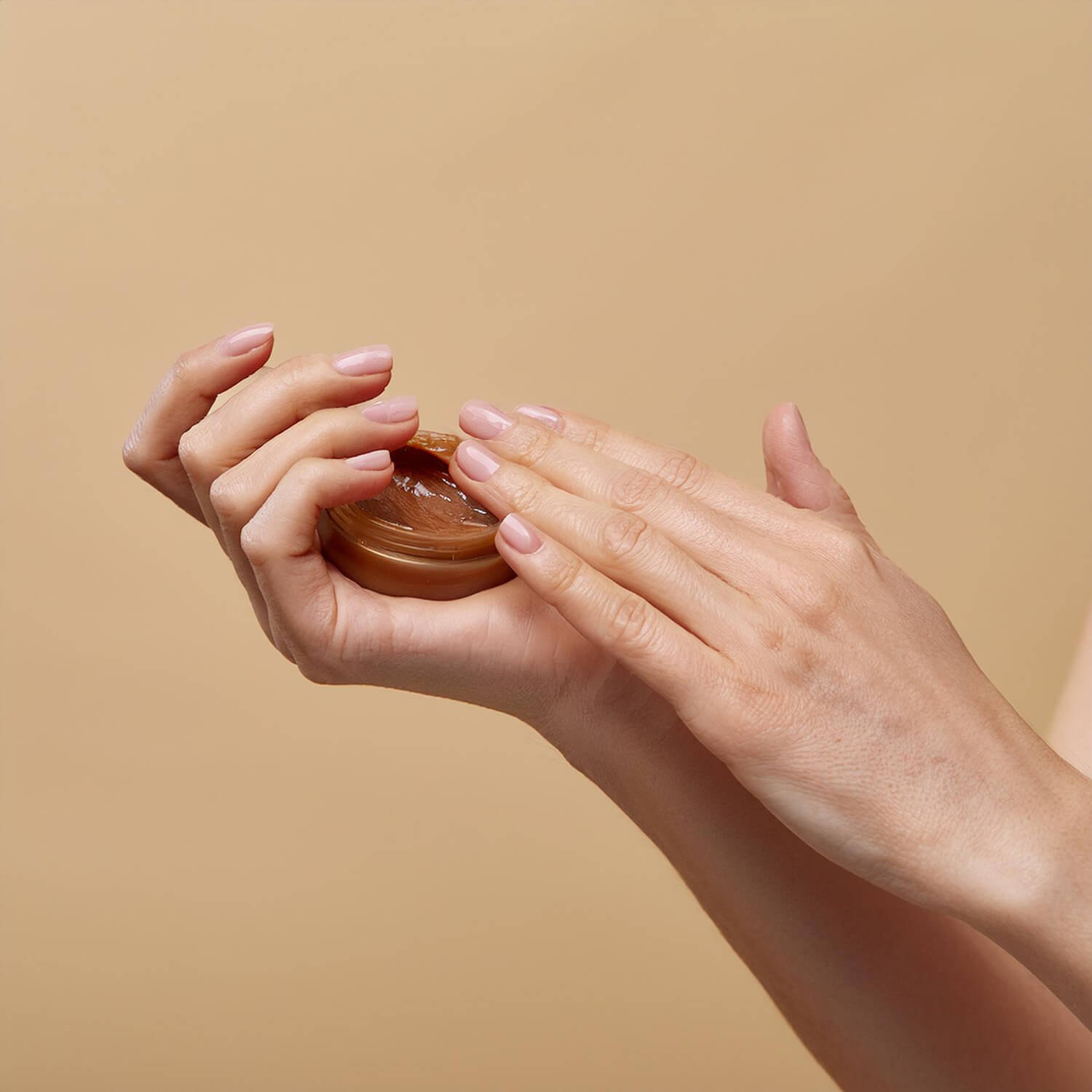 A view of hands applying a brown balm.