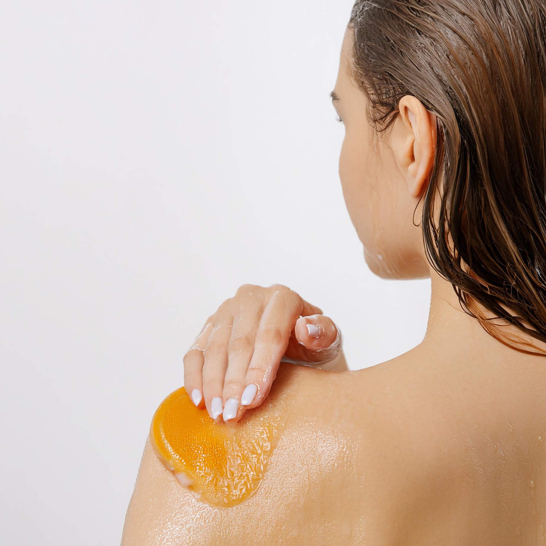 Vista de una mujer aplicándose gel de ducha sobre el cuerpo.
