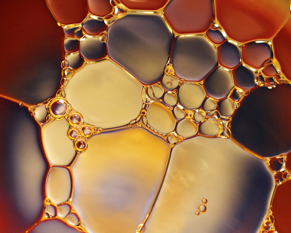 Melted palm oil with oily beads on the surface and a golden-yellow colour.