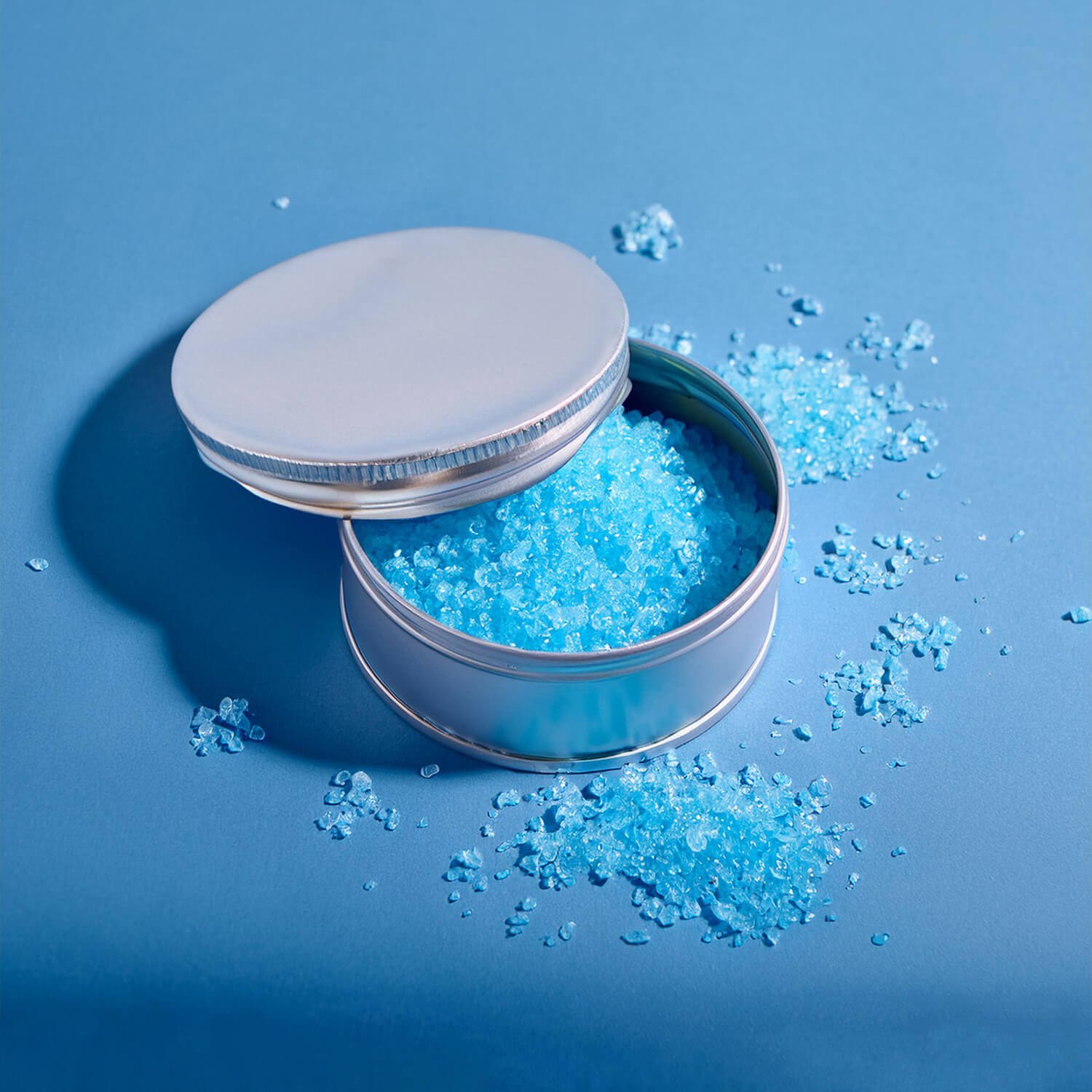 Pot argenté contenant un gommage douche moussant bleu.